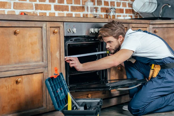 Jovem Reparador Roupa Trabalho Protetora Que Mede Forno Com Fita — Fotografia de Stock