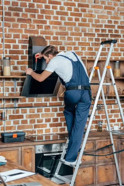 Профессиональный Молодой Мастер Стоящий Лестнице Закрепляющий Кухонный Капюшон Отверткой — стоковое фото