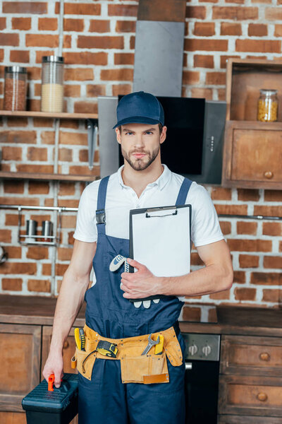 professional home master with toolbox and clipboard looking at camera