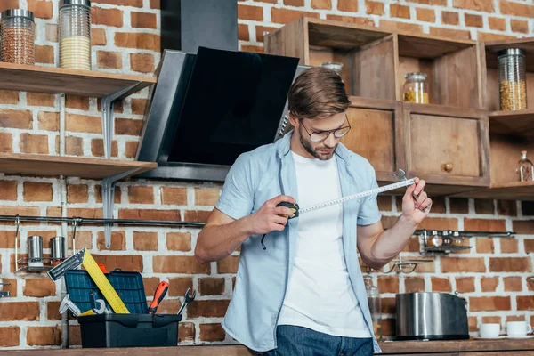 Young Man Holding Measuring Tape While Repairing Kitchen Hood — Stock Photo, Image