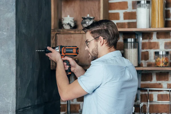 Vista Lateral Pared Perforación Hombre Joven Con Taladro Eléctrico Casa — Foto de Stock