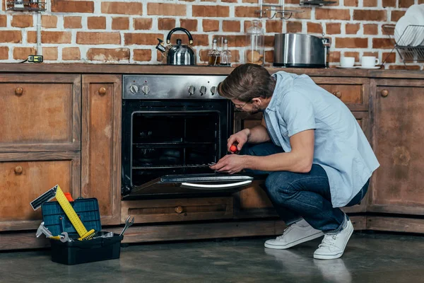 Jovem Casual Segurando Chave Fenda Durante Reparação Forno Cozinha — Fotografia de Stock