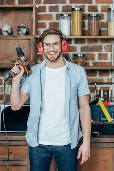 Handsome Young Man Eyeglasses Earmuffs Holding Electric Drill Smiling Camera — Stock Photo, Image