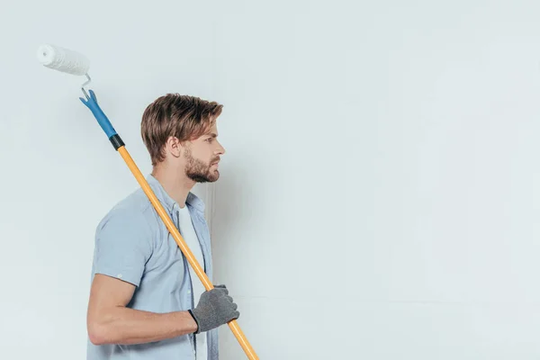 Side View Young Man Holding Paint Roller Looking Away Grey — Stock Photo, Image