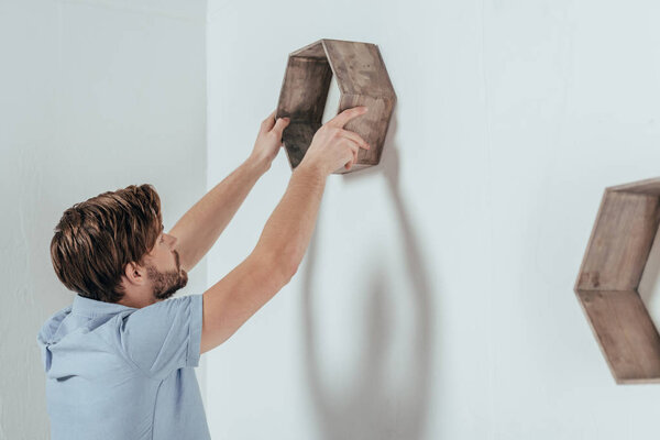 young man hanging wooden frame at home