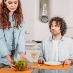 Novia poniendo ensalada en la mesa en la cocina