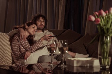 heteroseksüel çift kanepede akşam TV izlerken 