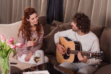 yakışıklı erkek şarkı gitar ile evde kız arkadaşına çalmak. 