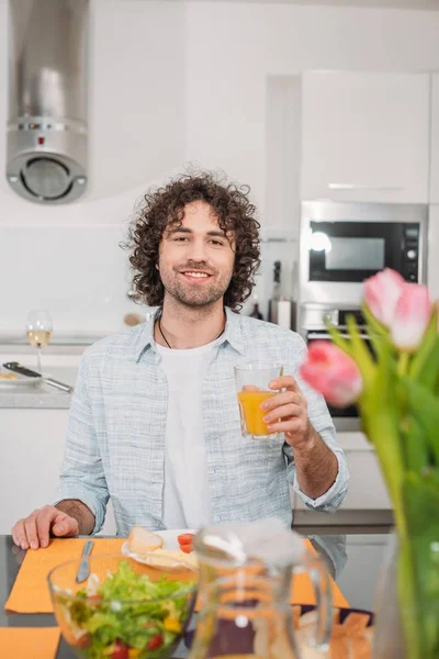 Усміхнений Чоловік Сидить Столом Їжею Тримає Склянку Апельсинового Соку — стокове фото