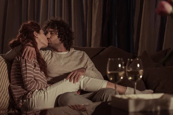 heterosexual couple kissing on sofa in evening