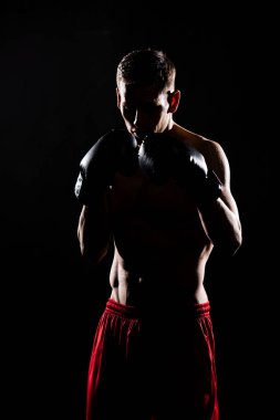 silhouette of young sportsman in boxing gloves boxing isolated on black clipart