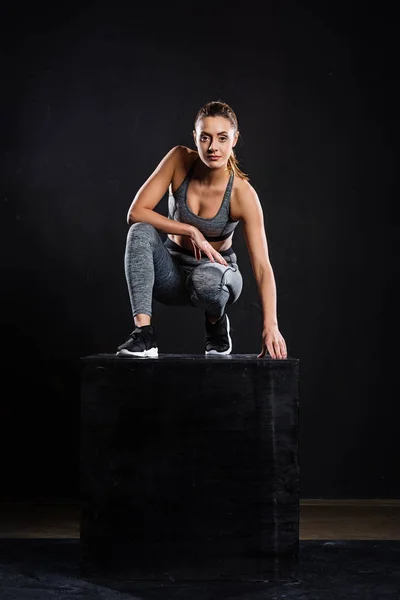 Athletic Young Sportswoman Crouching Black Cube Looking Camera Black — Stock Photo, Image