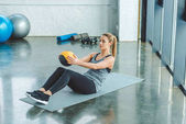 Sportlerin macht Übungen mit Ball im Fitnessstudio