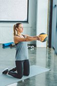Sportlerin macht Übungen mit Ball im Fitnessstudio