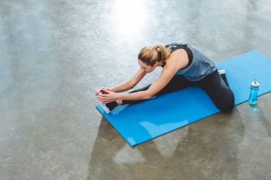 Genç sporcumuz yoga mat fitness salonunda egzersiz görünümünü yüksek açı