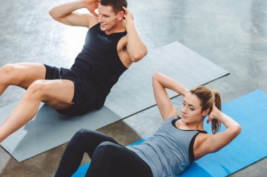 Sportif genç çiftin abs egzersiz fitness salonunda yoga paspaslar üzerinde yaparak yüksek açılı görünüş