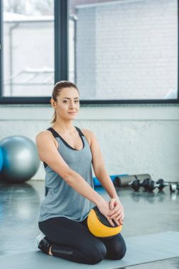 Mat içinde jimnastik salonu dinlenme topu ile gülümseyen sporcumuz
