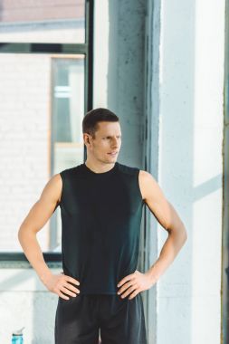 genç sporcu spor salonunda spor giyim ayakta akimbo portresi