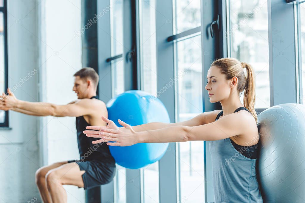 young man and woman exercising on fitness balls in gym