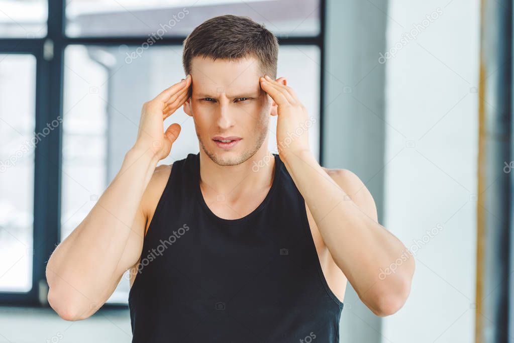 portrait of man in sportswear having headache 