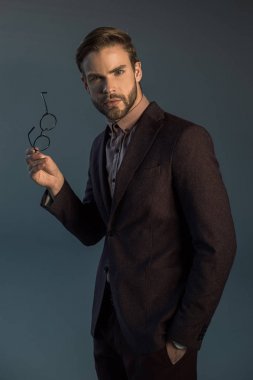 gözlük tutan ve gri izole kamera bakarak yakışıklı şık sakallı adam 