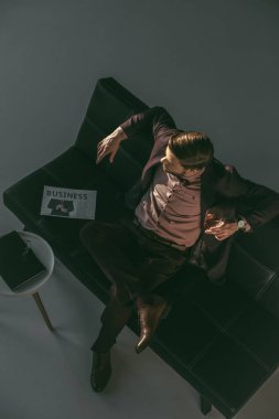 genç adam viski içme ve uzak kanepede otururken seyir yüksek açılı görünüş