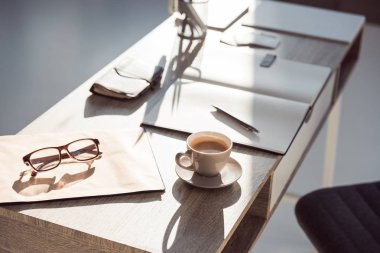 İşyerinde seçici odak Pano gözlük, fincan kahve ve ofis malzemeleri 