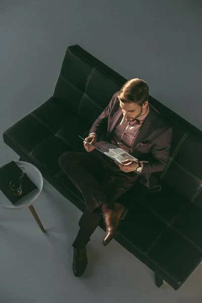 ソファに座って新聞を読む青年実業家のハイアングル — ストック写真