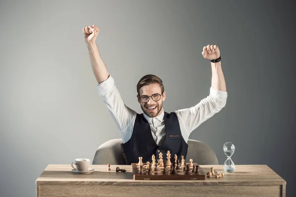 Triunfante Joven Hombre Negocios Gafas Sonriendo Cámara Mientras Juega Ajedrez —  Fotos de Stock