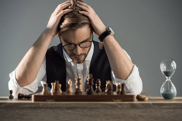 focused young businessman in eyeglasses playing chess 