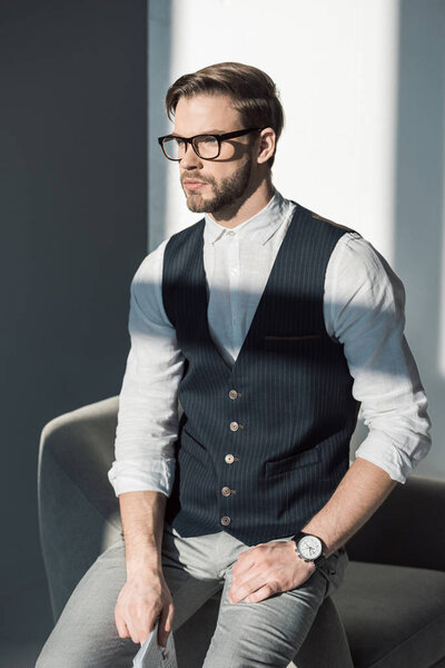 portrait of handsome stylish young businessman in eyeglasses looking away