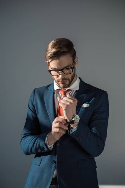 portrait of handsome young businessman wearing wristwatch isolated on grey