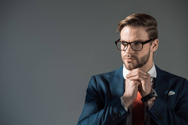 portrait of handsome stylish businessman in eyeglasses looking away isolated on grey