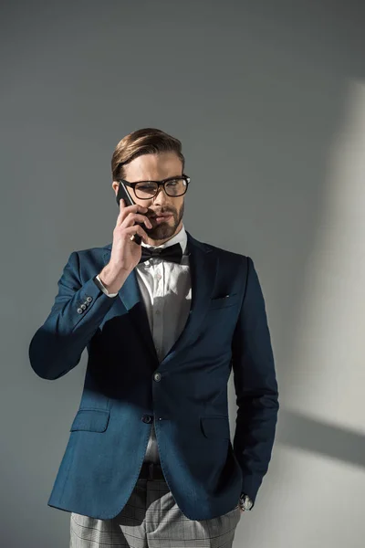 Portrait Stylish Businessman Eyeglasses Bow Tie Talking Smartphone Grey — Stock Photo, Image