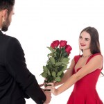 Boyfriend presenting bouquet of roses to girlfriend isolated on white