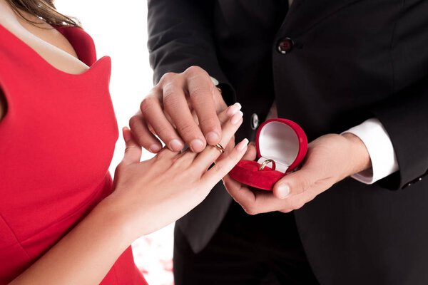 cropped image of boyfriend wearing ring on girlfriends finger isolated on white, valentines day concept