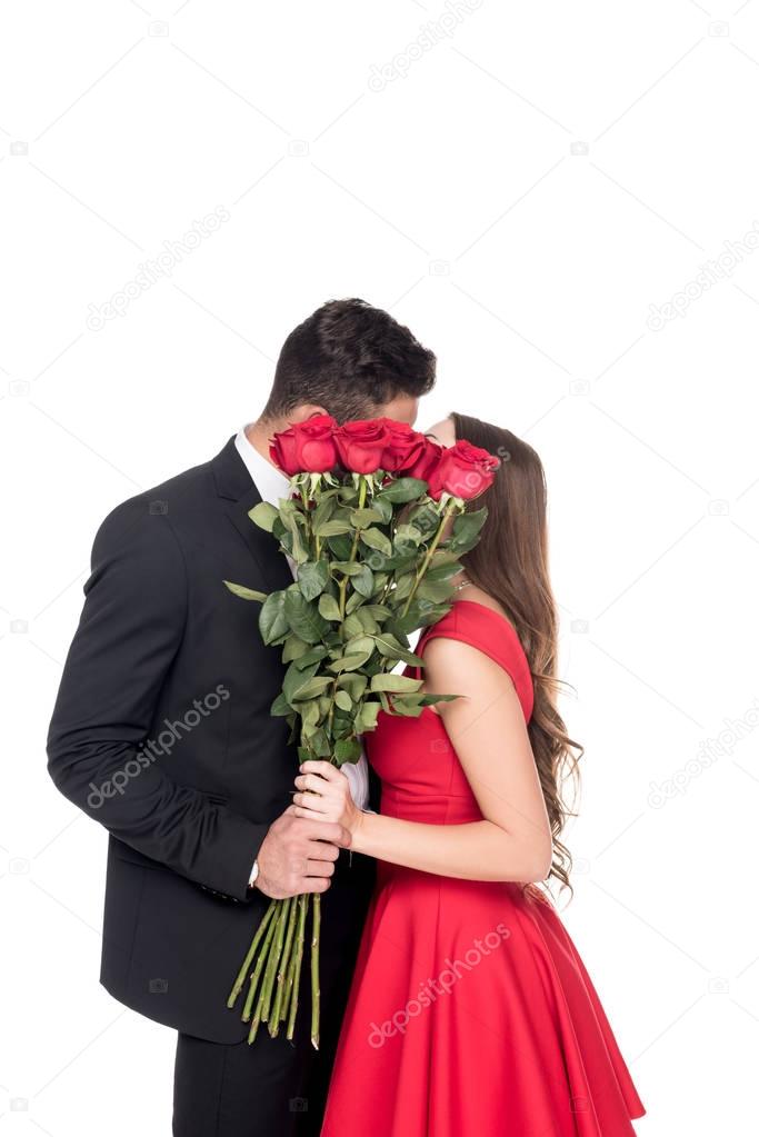 heterosexual couple kissing and covering faces with bouquet isolated on white