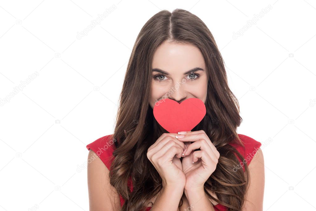 smiling girl covering mouth with paper heart isolated on white, valentines day concept