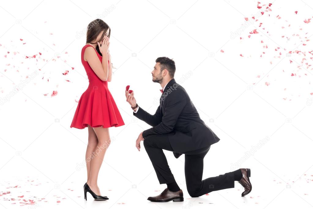 side view of boyfriend proposing girlfriend and standing on knee isolated on white, valentines day concept