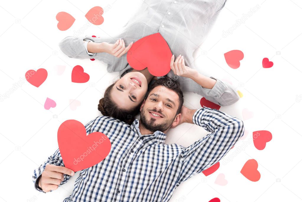 overhead view of couple lying with paper hearts isolated on white, valentines day concept