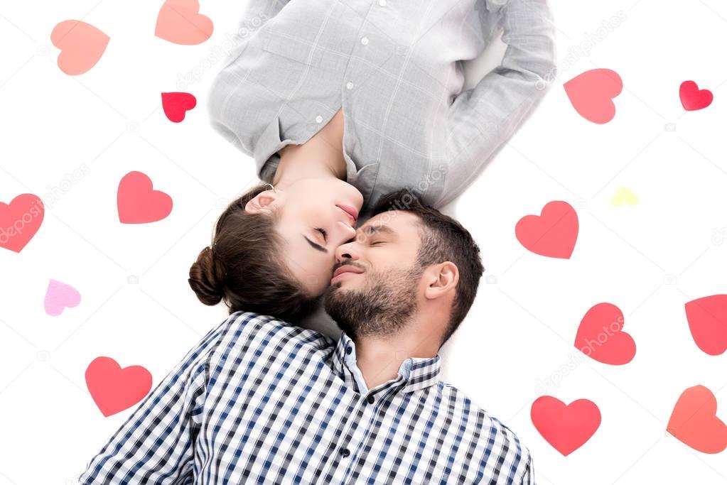 overhead view of couple lying with paper hearts isolated on white, valentines day concept