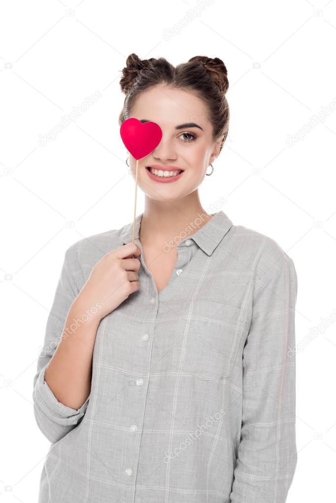 smiling girl covering eye with paper heart isolated on white, valentines day concept 