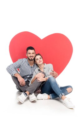 happy couple sitting near big heart on white, valentines day concept clipart