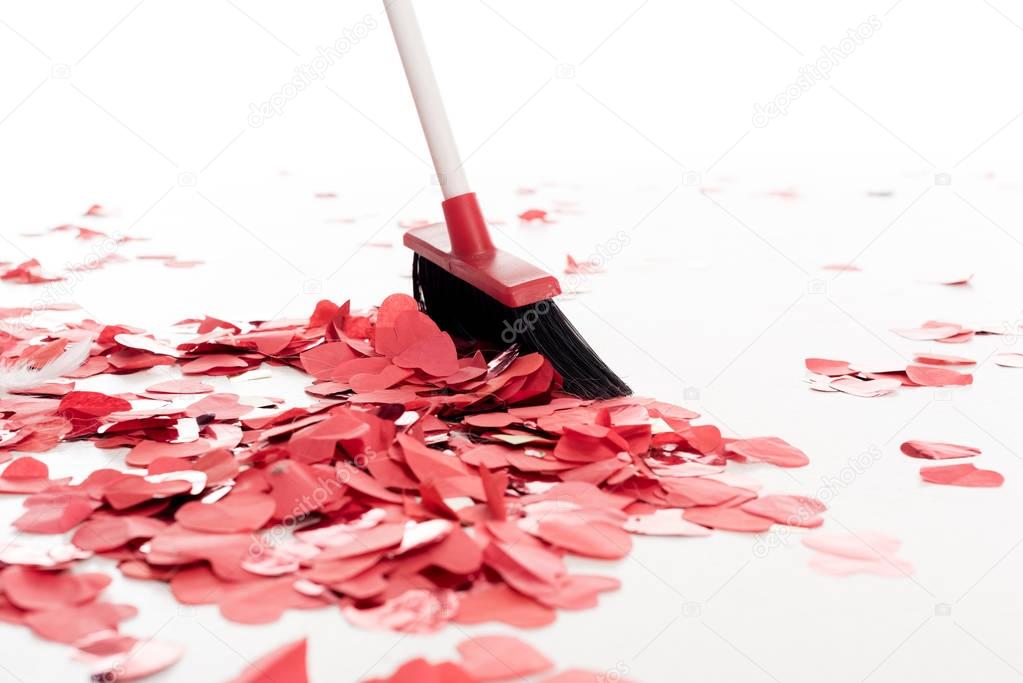 broom sweeping out heart shaped confetti isolated on white, valentines day concept