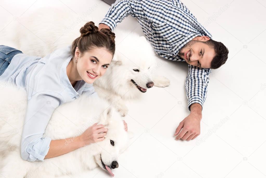 overhead view of couple lying with dogs on white