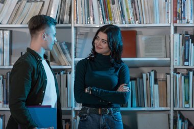 Kitaplığı'nda konuşan öğrenciler gülümseyen genç