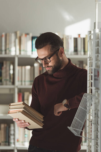 handsome man looking at books in library
