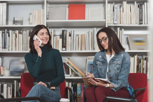 Attraente Studente Parlando Smartphone Biblioteca — Foto stock gratuita