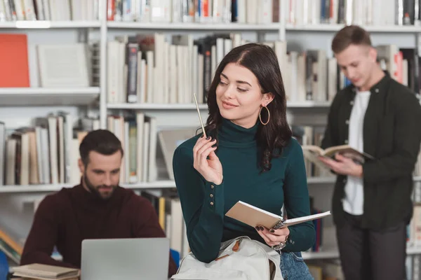 Wesoły Kobieta Patrząc Ołówek Bibliotece — Zdjęcie stockowe