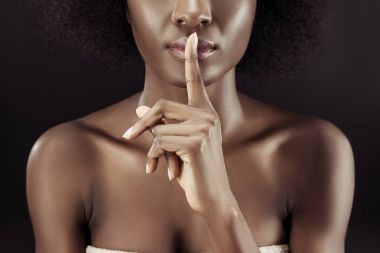 cropped shot of african american woman showing silence gesture isolated on black clipart